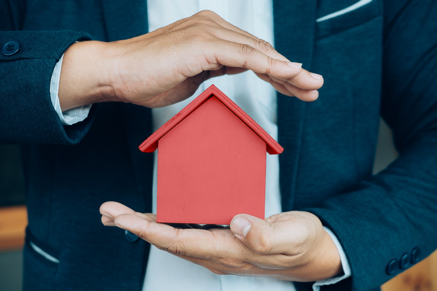 Business man hand hold house model saving small house u